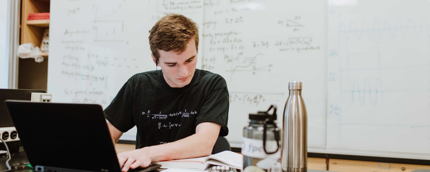 a college physics major sitting at a table behind an open laptop