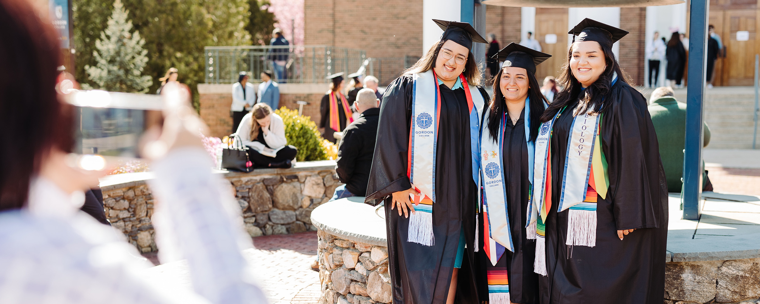 girls standing inform of the bell getting a graduation photo