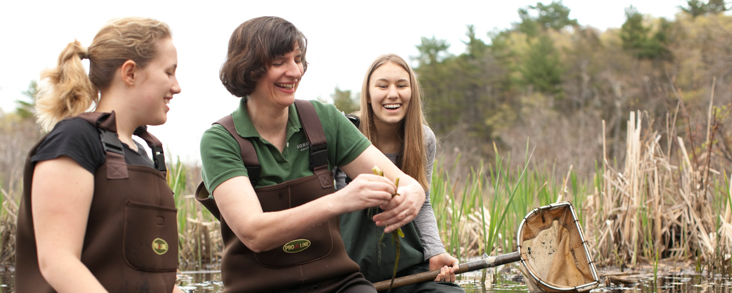 a biology professor at Gordon College with two students laughing and learning in a conservation area