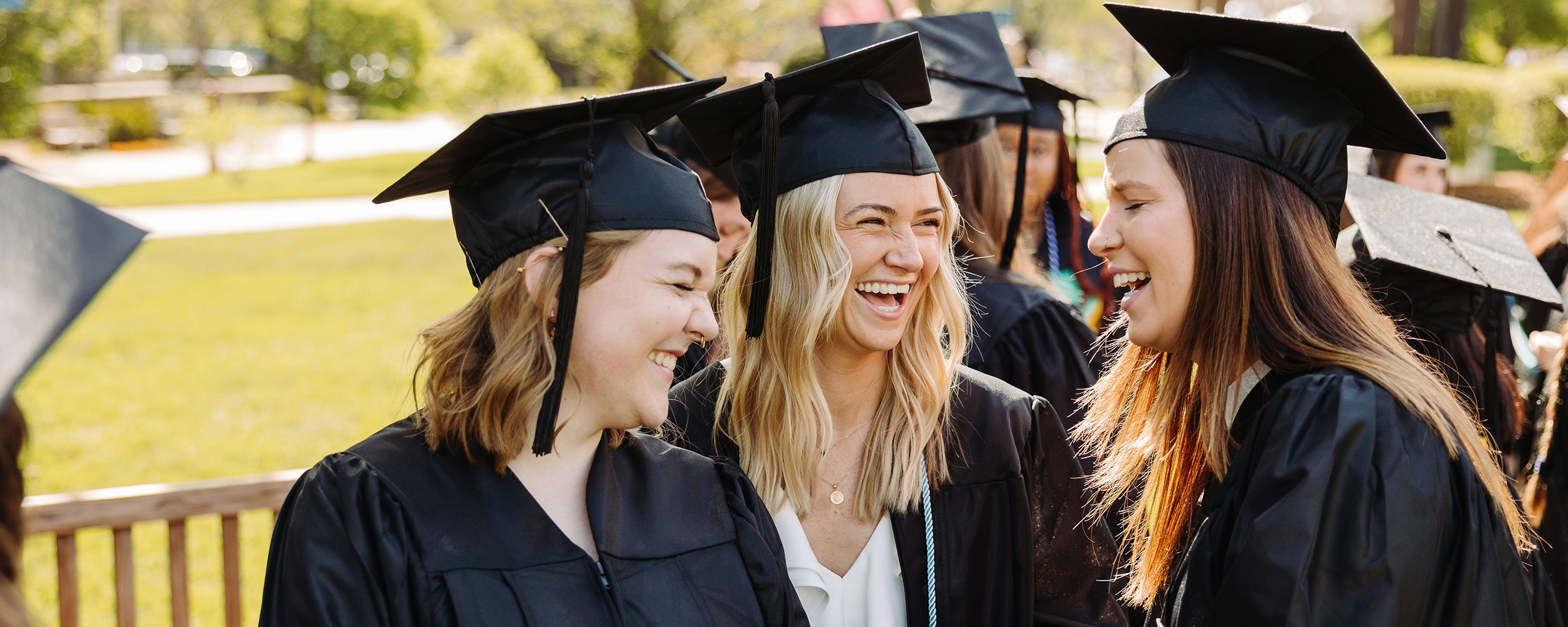 Photo of Gordon College graduates laughing with each other during commencement