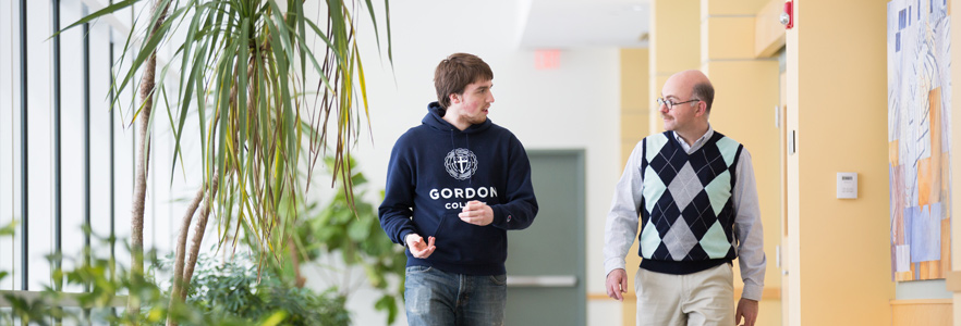 a Gordon College student walking through the hallway with his academic advisor