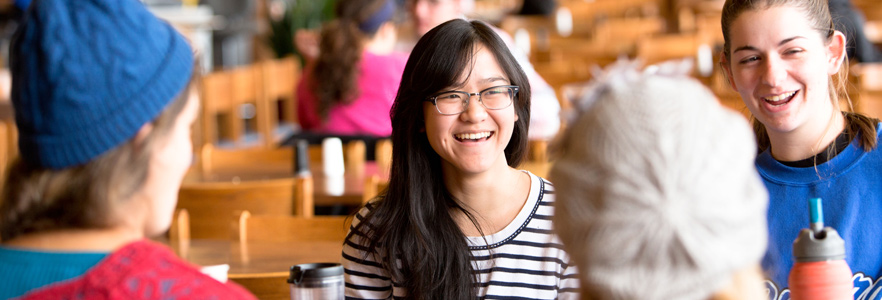 Gordon College students sitting together and laughing in the dining hall.