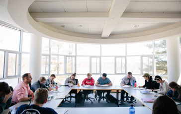 First-year students at Gordon College sitting at a table and taking notes on the Academic Guide.